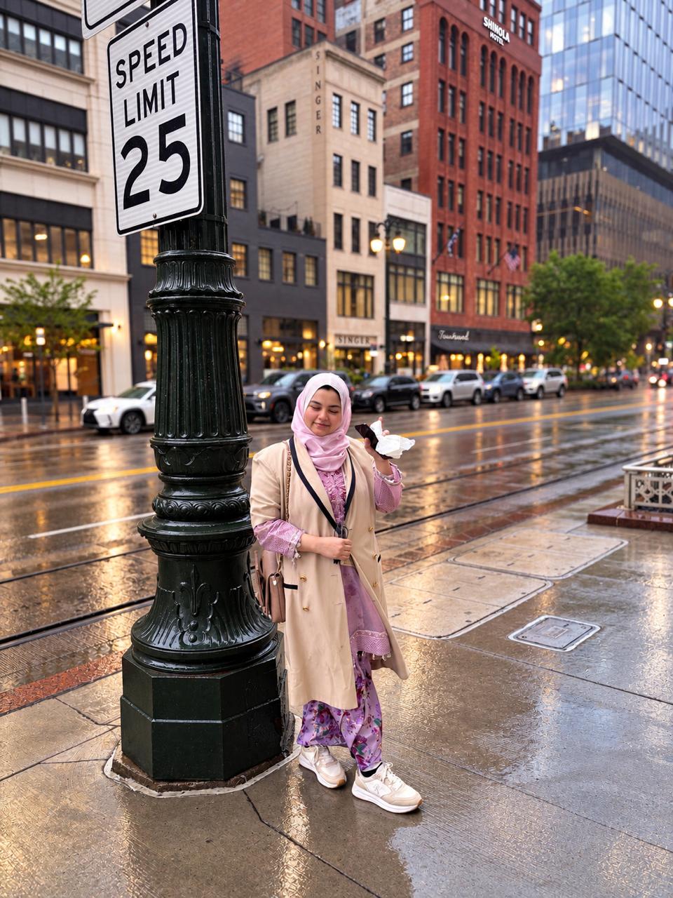 The researcher stands on a wet city street next to a speed limit sign
