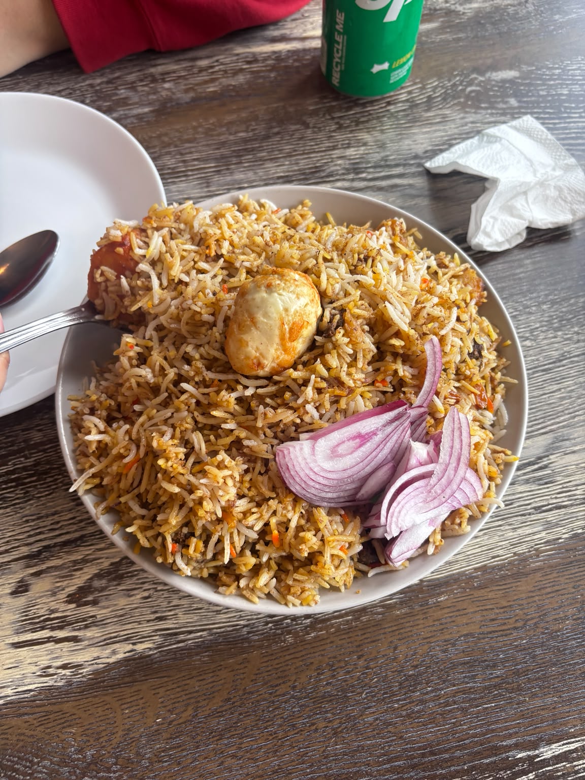 A plate of biryani with egg and red onion